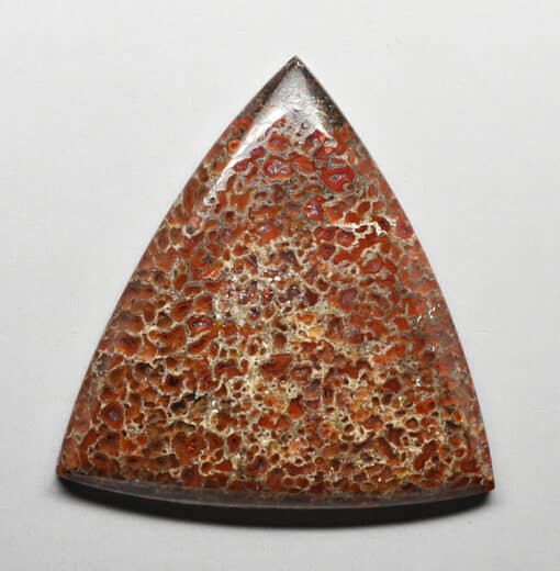 A triangular shaped piece of red and brown stone.