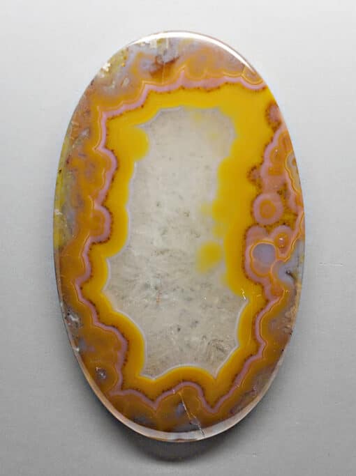 A yellow and orange agate pendant on a white surface.