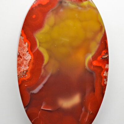 A red and yellow agate pendant on a white surface.