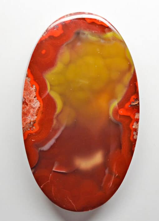 A red and yellow agate pendant on a white surface.
