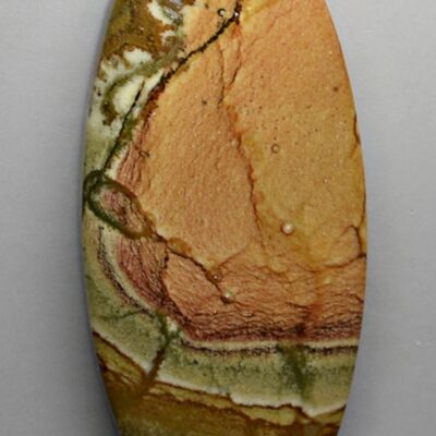 A yellow and brown oval shaped stone on a white surface.