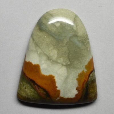 A piece of green and orange jasper on a white surface.