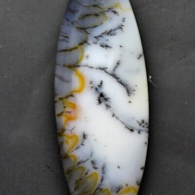 A white and yellow agate pendant on a black surface.