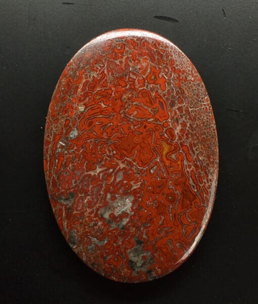 A piece of red jasper on a black surface.