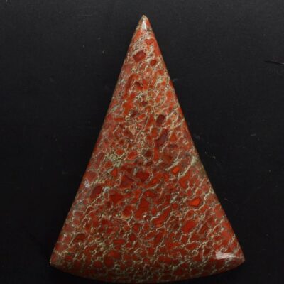 A triangular piece of red coral on a black surface.