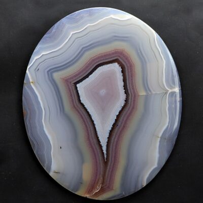 A circular piece of agate on a black surface.