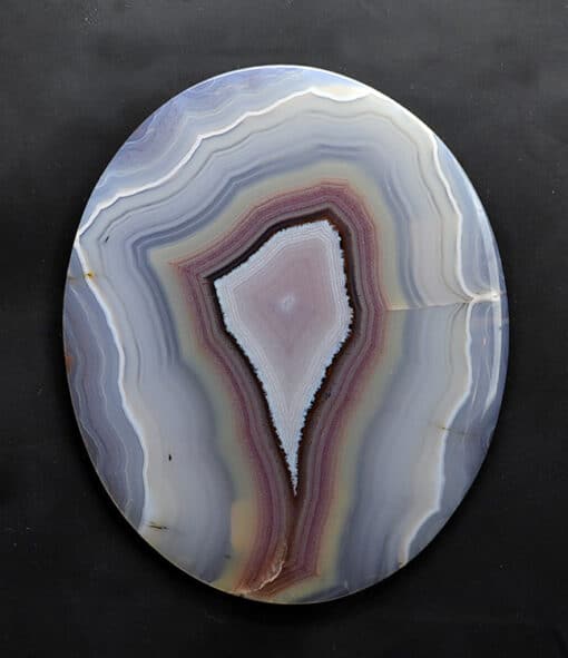 A circular piece of agate on a black surface.