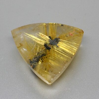 A triangular piece of yellow quartz on a white surface.