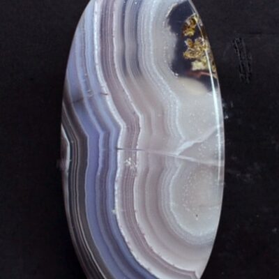 A blue and purple agate pendant on a black surface.