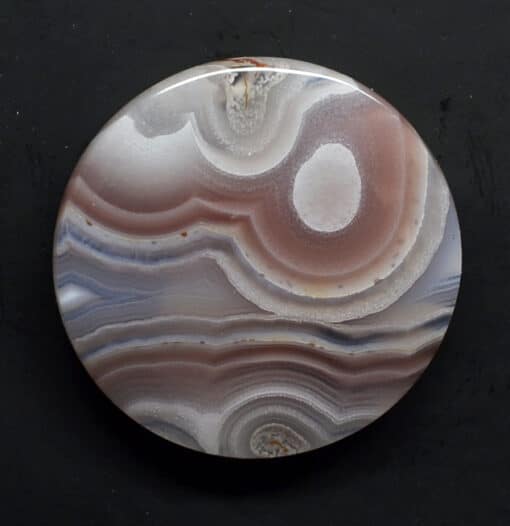 A round piece of agate with white and brown swirls.