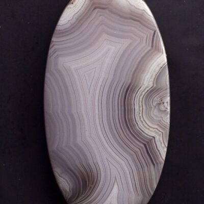A large oval piece of agate on a black surface.