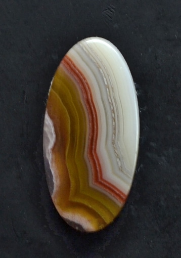 An oval piece of agate on a black surface.