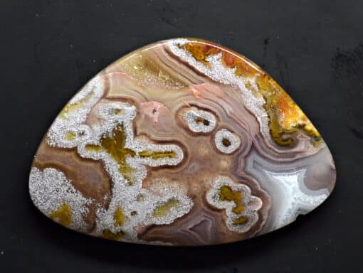 A triangular piece of agate on a black surface.