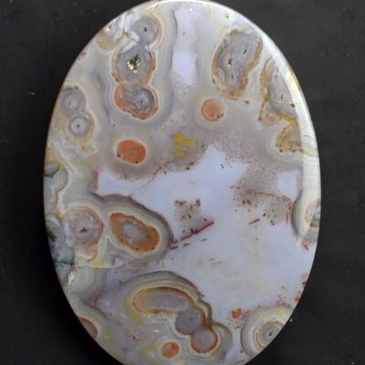 A round piece of agate on a black surface.