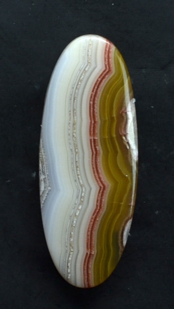 An oval piece of agate on a black surface.