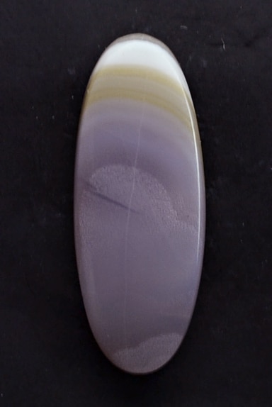 A purple oval agate stone on a black surface.
