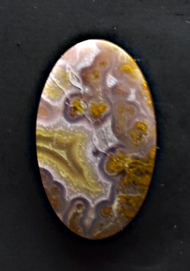 A brown and yellow agate pendant on a black surface.