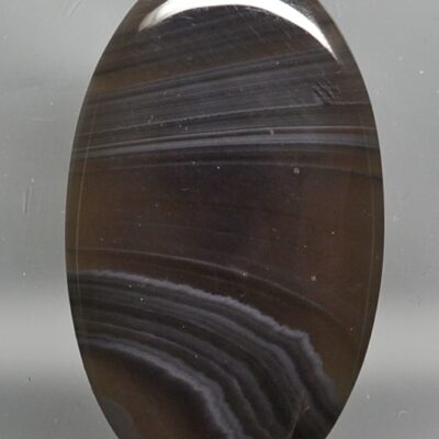 A black oval agate stone on a white surface.