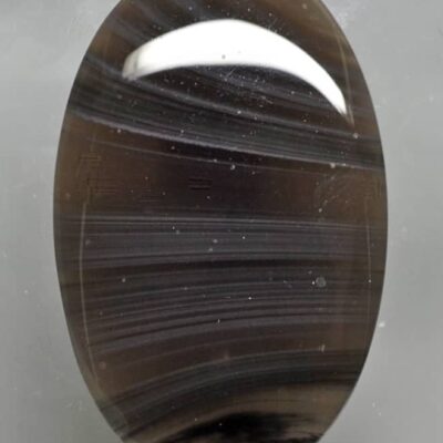 An oval black agate stone on a white surface.