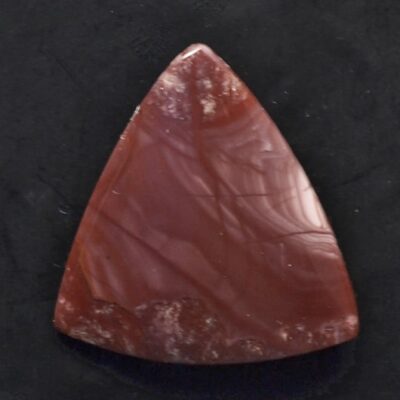 A piece of red jasper on a black surface.
