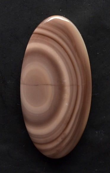 A brown agate oval on a black surface.