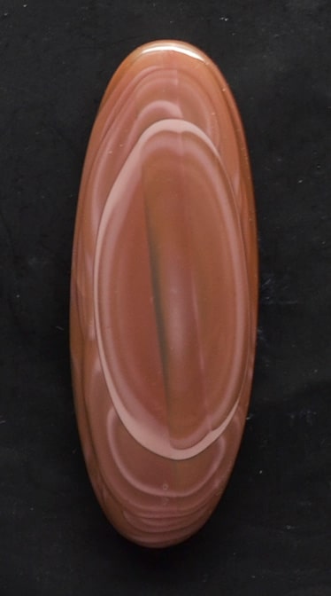 A piece of brown agate on a black surface.