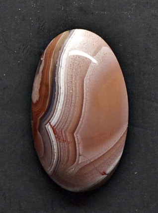 An oval agate stone on a black surface.