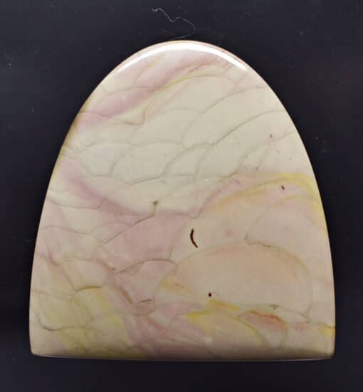 A piece of pink and yellow marble on a black surface.