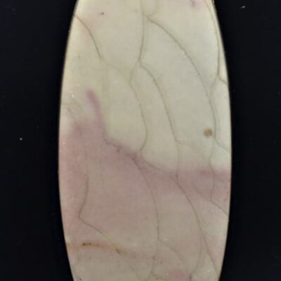 A pink and white stone pendant on a black surface.