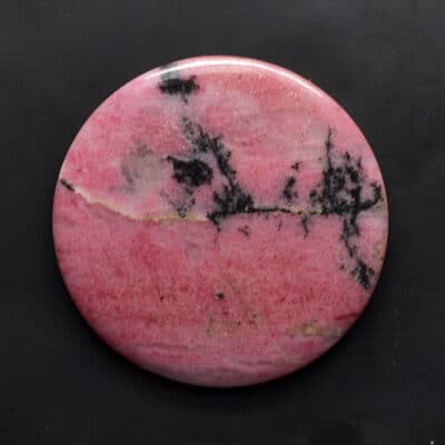 A pink and black marble button on a black surface.