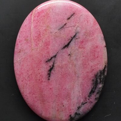 A round pink stone with a black background.