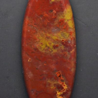 A red and yellow oval shaped stone on a black surface.