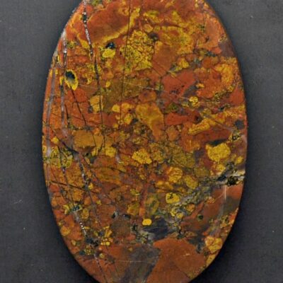 A round piece of red and orange marble on a black background.