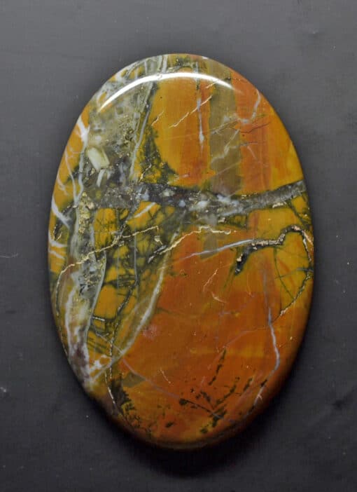 A round piece of orange and black marble on a black surface.
