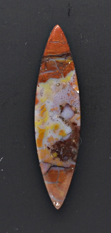 An orange and brown stone pendant on a black surface.