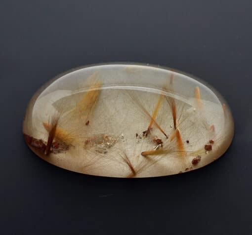 A piece of Quartz with Amphibole 133.77 ct. oval cabochon 65.3 x 29.5 mm. y90711 with dried grass on it.