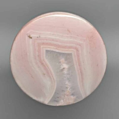 A pink agate button on a grey background.