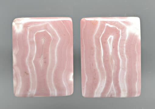 A pair of pink agate slabs on a gray surface.