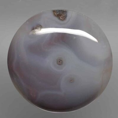 A purple agate ball on a gray surface.