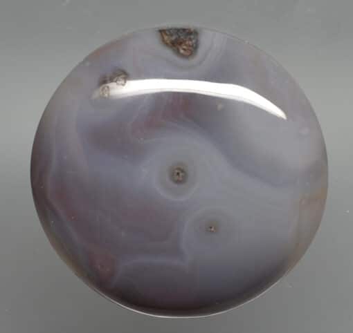 A purple agate ball on a gray surface.