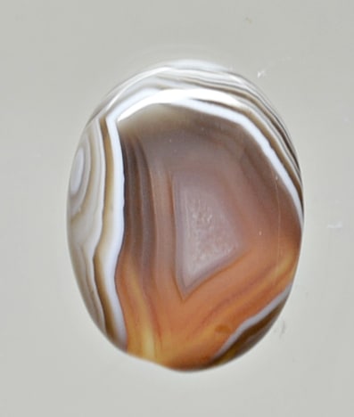 A brown and white agate stone on a white surface.