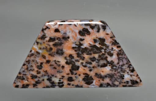 A triangle shaped piece of brown and black marble.