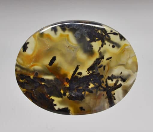 A round piece of agate with black and yellow swirls.