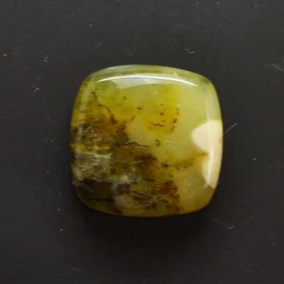 A green jade cabochon on a black surface.