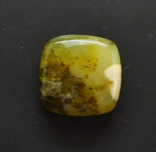 A green jade cabochon on a black surface.