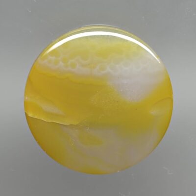 A yellow and white agate ball on a gray surface.