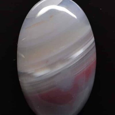 A white and red agate stone on a black surface.