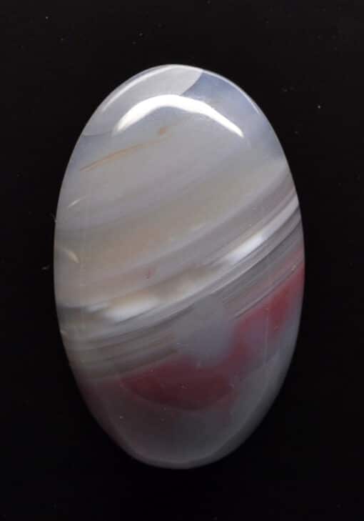 A white and red agate stone on a black surface.