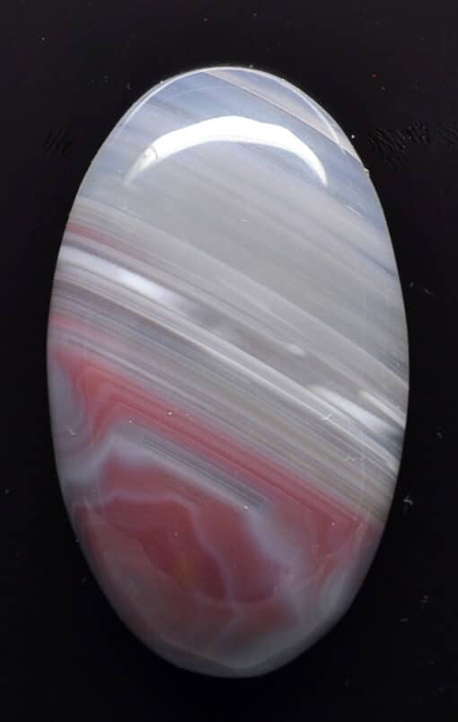 A white and red agate stone on a black surface.