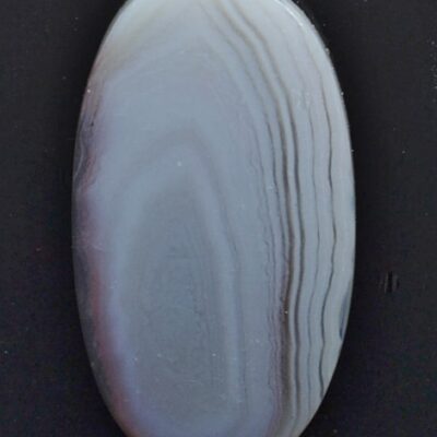 A white and gray agate stone on a black surface.
